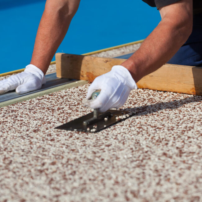 Resin driveway worker showing hands holiding a trowel on resin being laid down on drive